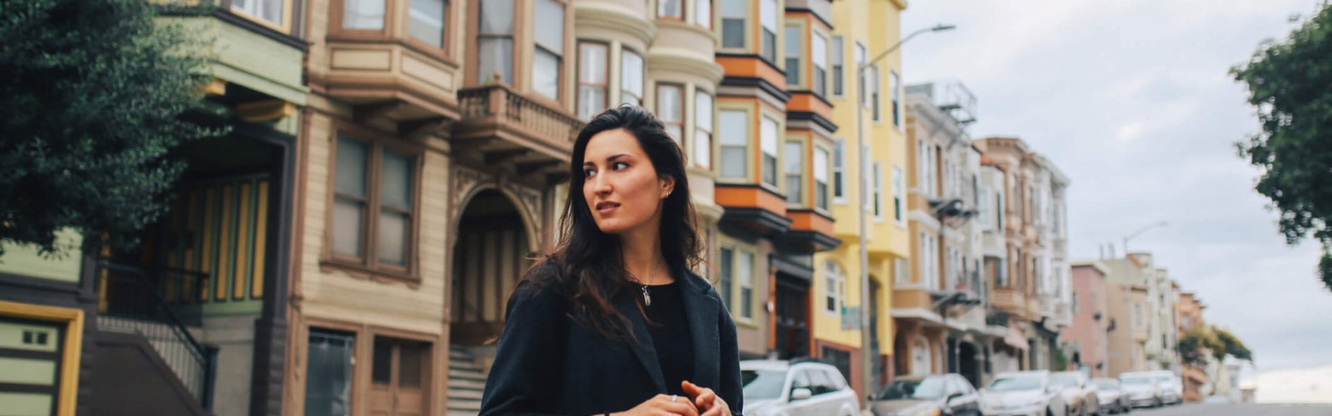 woman takes in the sites while walking among San Francisco's Painted Lady houses
