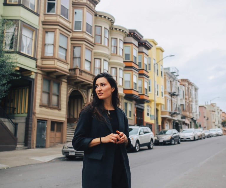 woman takes in the sites while walking among San Francisco's Painted Lady houses