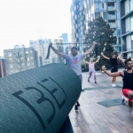 close crop of a yoga mat with the BEI logo, and people doing yoga in the background
