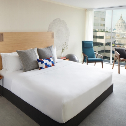 hotel room with large white bed and seating area by window