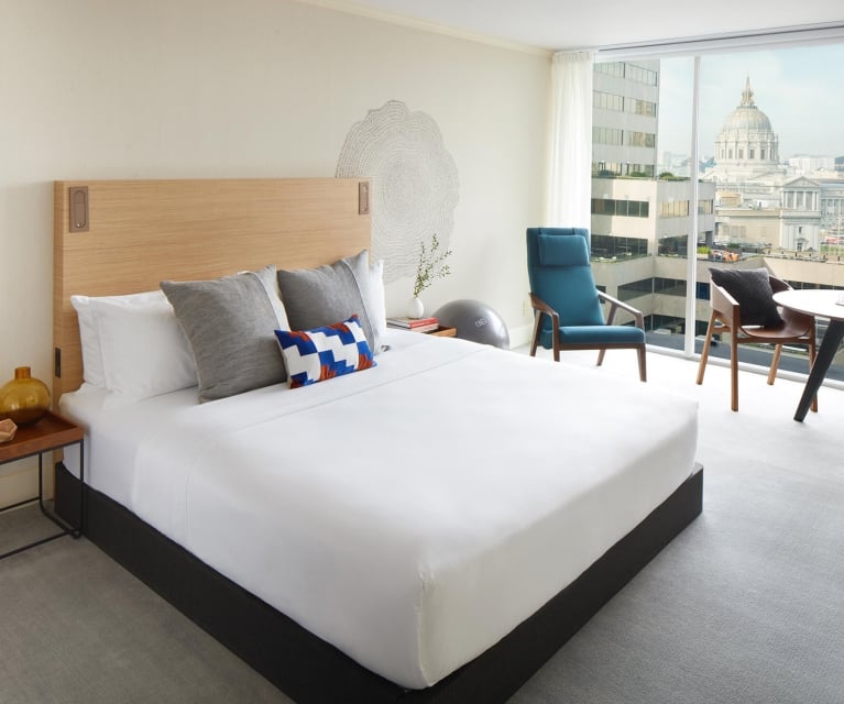 hotel room with large white bed and seating area by window