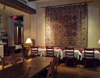 Kokkari restaurant interior with tables and wall tapestry