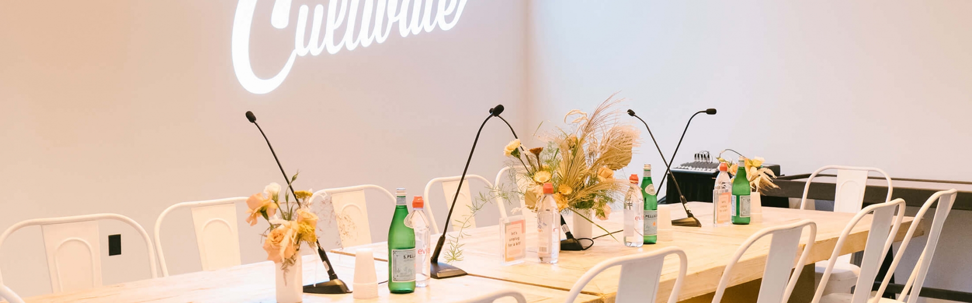 board room table with white metal chairs and artful place settings