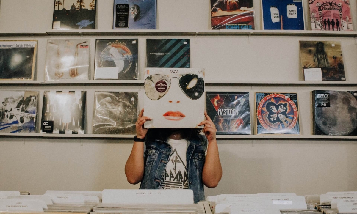 woman holds record in front of her, giving illusion her face is the record cover.