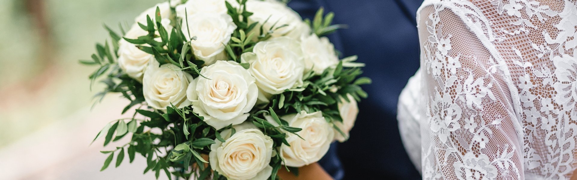 close up of wedding bouquet with bride and groom embracing