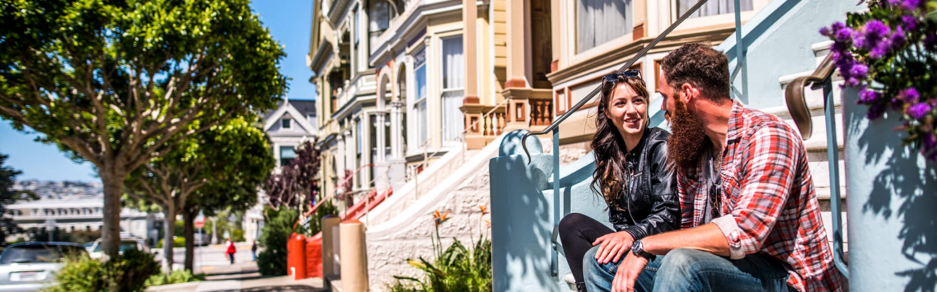 couple sits on stoop of painted lady home with corgi