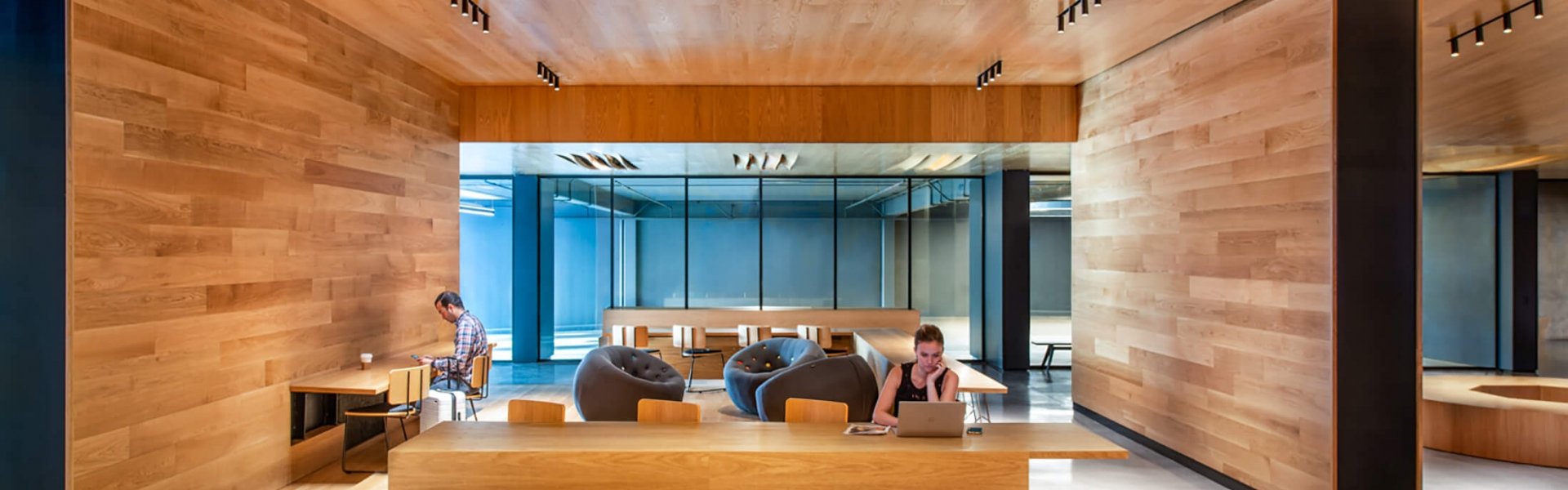 people gather in communal workspace which is entirely wooden and modern