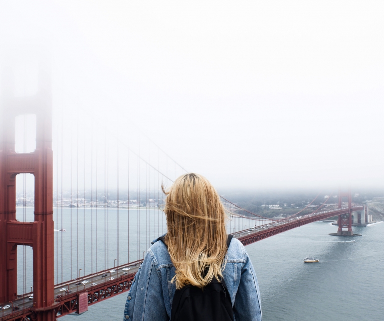 woman stand and looks at golden gate bridge in the fog